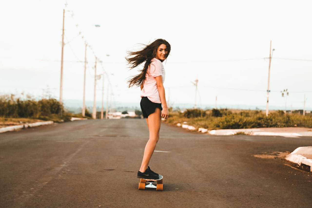 Enjoy a moment of freedom as a young woman skateboards down an empty road.